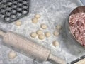 on the kitchen table are several dumplings with meat, a wooden rolling pin and a form for sculpting dumplings Royalty Free Stock Photo