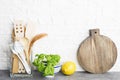Kitchen tools, olive cutting boan a kitchen shelf against a white brick wall. Fresh basil and lemon. White and black Royalty Free Stock Photo
