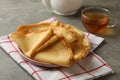 Kitchen towel with plate of thin pancakes and tea on gray table Royalty Free Stock Photo