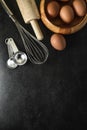 Kitchen utensils and baking ingredients: egg and flour on black background, copy-space. Royalty Free Stock Photo