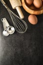 Kitchen utensils and baking ingredients: egg and flour on black background. Royalty Free Stock Photo