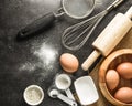 Kitchen utensils and baking ingredients: egg and flour on black background. Royalty Free Stock Photo