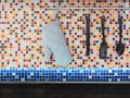 Kitchen utensils hanging over colorful mosaic wall tiles. Royalty Free Stock Photo