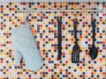 Kitchen utensils hanging over colorful mosaic wall tiles. Royalty Free Stock Photo