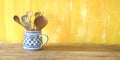 Kitchen utensils in an old jug, good copy space on painted yellow wall,large copy space Royalty Free Stock Photo