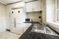 Kitchen with a wall clad in smooth glossy white cabinets with stainless steel pulls, a black countertop and two attached white Royalty Free Stock Photo