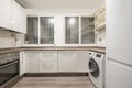 kitchen with white cabinets, brownstone worktops, twin barred windows and a white washing machine and fridge Royalty Free Stock Photo