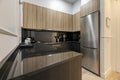 Kitchen with wooden furniture in the upper part, black furniture in the lower part, black marble countertop and integrated