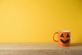 Kitchen wooden shelf background and orange coffee cup with jack o lantern spooky face