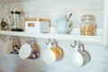 Kitchen wooden shelf with tea leaves in gold box and accessories, blue sugar bowl with spoon, strainer, press. Many colorful cups Royalty Free Stock Photo