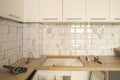 Kitchen with wooden worktop, white cabinets and white metro tile. under reconstruction
