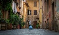 A kitchen worker carrys trash and rubbish out in Beautiful old street in Trastevere. It`s a romantic district of Rome, Italy