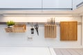 Kitchenware hanging on the rail in the white glossy kitchen