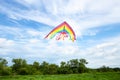 Kite fly on blue sky with white clouds and green field Royalty Free Stock Photo