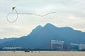 Kite flying in cloudy sky above lake water on city buildings and mountain peaks background, Hong Kong Royalty Free Stock Photo