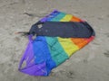 Kite in rainbowcolors with black threads laying on the beach of Velsen Netherlands Royalty Free Stock Photo