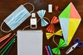 Kite, school materials a mouth mask and liquid hand sanitizer on wooden table