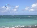 Kite surfer on blue water, with blue kite high in the air,