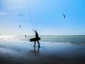 Kite surfer on the ocean beach. Silhouette of kite surfer across the sea shore. Royalty Free Stock Photo