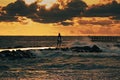 Kite surfer running around the pier in the stormy sea lit by the sunset light under dramatic evening clouds Royalty Free Stock Photo