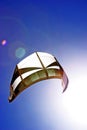 Kite surfers kite flying in the dark blue sky with sun beaming on. Royalty Free Stock Photo