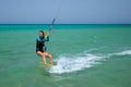 Kite surfing girl in swimsuit with kite in sky on board in blue sea riding waves with water splash. Recreational activity, Royalty Free Stock Photo