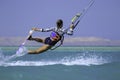 Kite surfing girl in sexy swimsuit with kite in sky on board in blue sea riding waves with water splash. Recreational activity Royalty Free Stock Photo