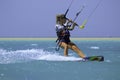 Kite surfing girl in sexy swimsuit with kite in sky on board in blue sea riding waves with water splash. Recreational activity Royalty Free Stock Photo