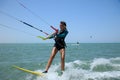 Kite surfing girl in swimsuit with kite in sky on board in blue sea riding waves with water splash. Recreational activity, Royalty Free Stock Photo