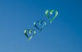 Kite with with three green and blue hearts flying in the sky