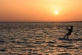 Kite surfing girl in swimsuit with kite in sky on board in blue sea riding waves with water splash. Recreational activity,