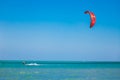 Kitesurfer with red kite gliding over the Red sea.