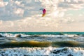 Kitesurfer rides kite through surfing waves of stormy Black sea breaking on sandy seashore
