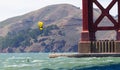 Kitesurfer with yellow sail surfing under the South Structure of the Golden Gate Bridge