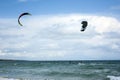 Kitesurfers ride kites on Black Sea at sandy Beach In Bulgaria, Sozopol on sunny day at sunset on blue sky and clouds background. Royalty Free Stock Photo