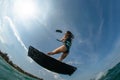 Kitesurfing girl in black sexy swimsuit with kite in sky on board in blue sea riding waves with water splash. Recreational Royalty Free Stock Photo
