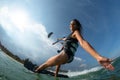 Kitesurfing girl in black sexy swimsuit with kite in sky on board in blue sea riding waves with water splash. Royalty Free Stock Photo