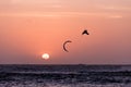 Kitesurfing jump, man kite surfer jumping at sunset golden hour silhouette on orange background