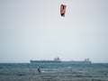 Kitesurfing During a Windy Day with a Very Rough Sea and Industrial Boat in the background Royalty Free Stock Photo