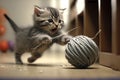 kitten playing with ball of thread, batting it around and chasing after it