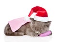 Kitten in red christmas hat sleeping on pillow. isolated on white background Royalty Free Stock Photo