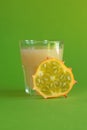 Kiwano slice, exotic vegetable cucumis metuliferus and a glass of fruit juice on a green background. Soft focus. Vegetarian food