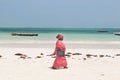 Local Zanzibar woman in bright robe on the beach near the Indian