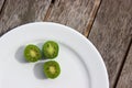 Kiwi berries (arctic kiwifruit) on white plate on wooden table