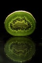 Kiwi slice backlit close up isolated on black background with reflection Royalty Free Stock Photo