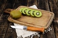 Kiwi fruit slice in cutting board have knife isolated on wood background Royalty Free Stock Photo