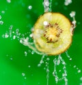 Kiwi fruit in a spray of water on a green background Royalty Free Stock Photo