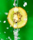 Kiwi fruit in a spray of water on a green background Royalty Free Stock Photo