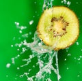 Kiwi fruit in a spray of water on a green background Royalty Free Stock Photo