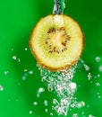 Kiwi fruit in a spray of water on a green background Royalty Free Stock Photo